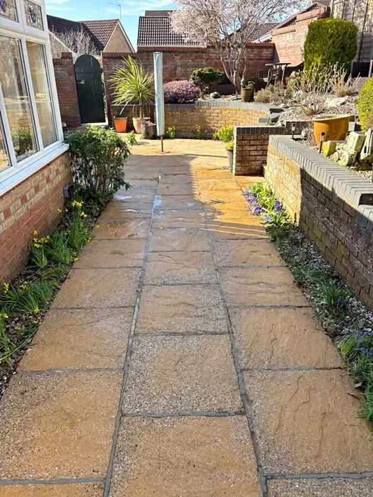 The same garden patio path cleaned back to its original warm sandstone colour